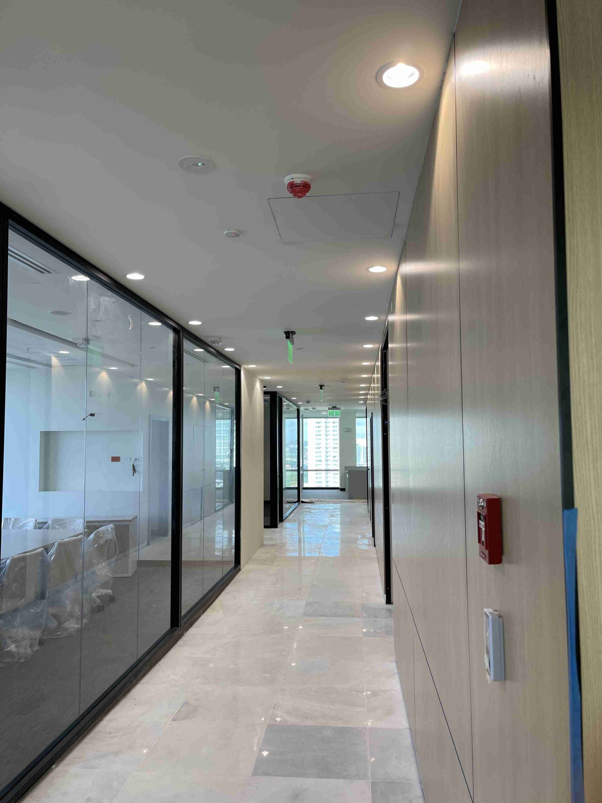 Pasillo de oficina moderna con iluminación LED y paredes de cristal.