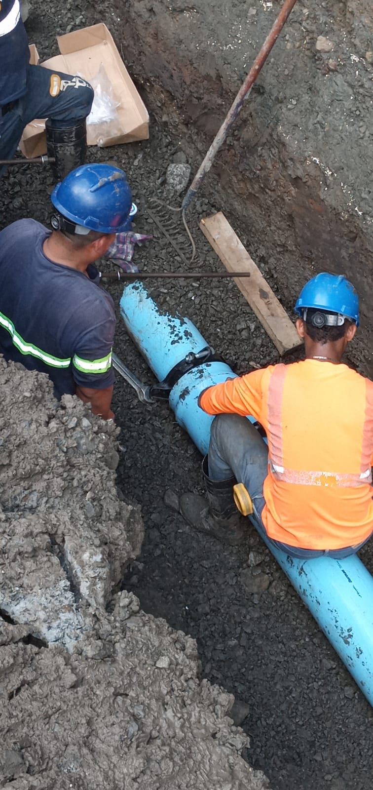 Trabajadores instalando tuberías subterráneas de PVC en proyecto de construcción.
